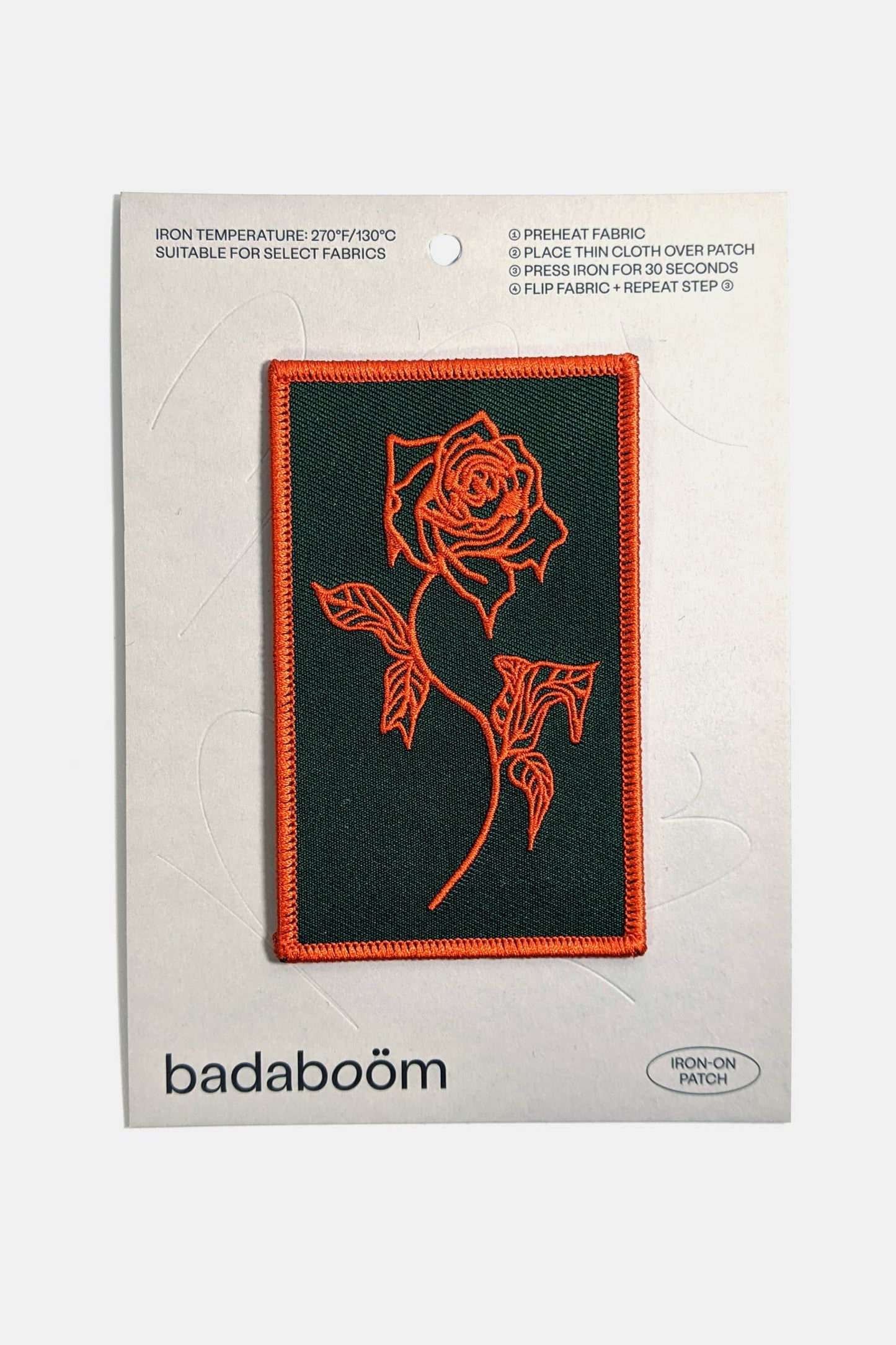 An embroidered rectangular patch from Badaboöm Studio, featuring a red Rose design on a black background, shown on a card against a white background.