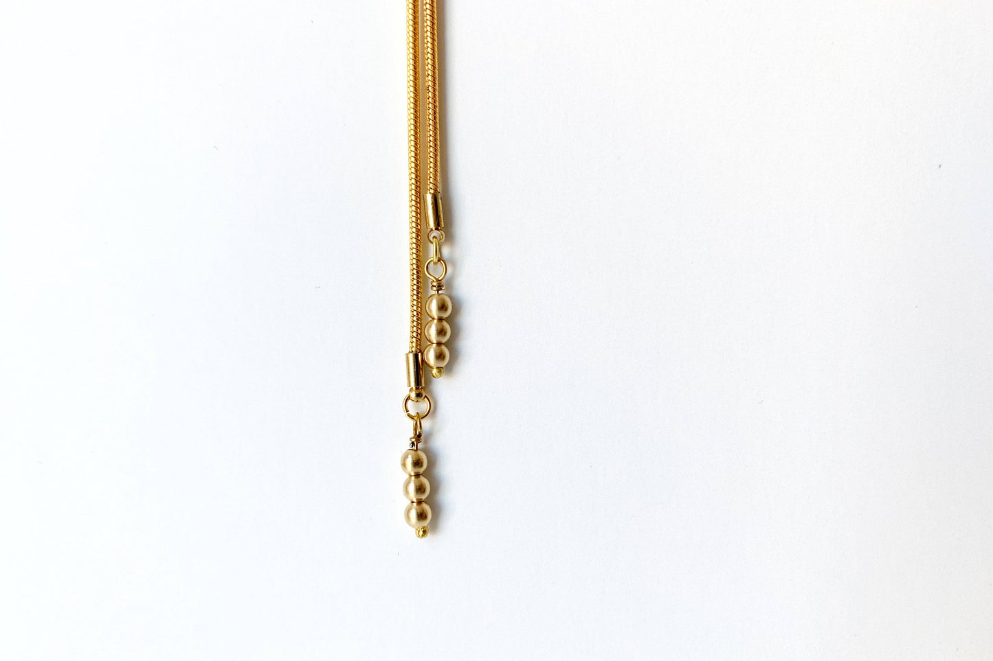Close up of the ends of the TROLLOP Mini Bolo Tie from Lord Violet shown against a white background.
