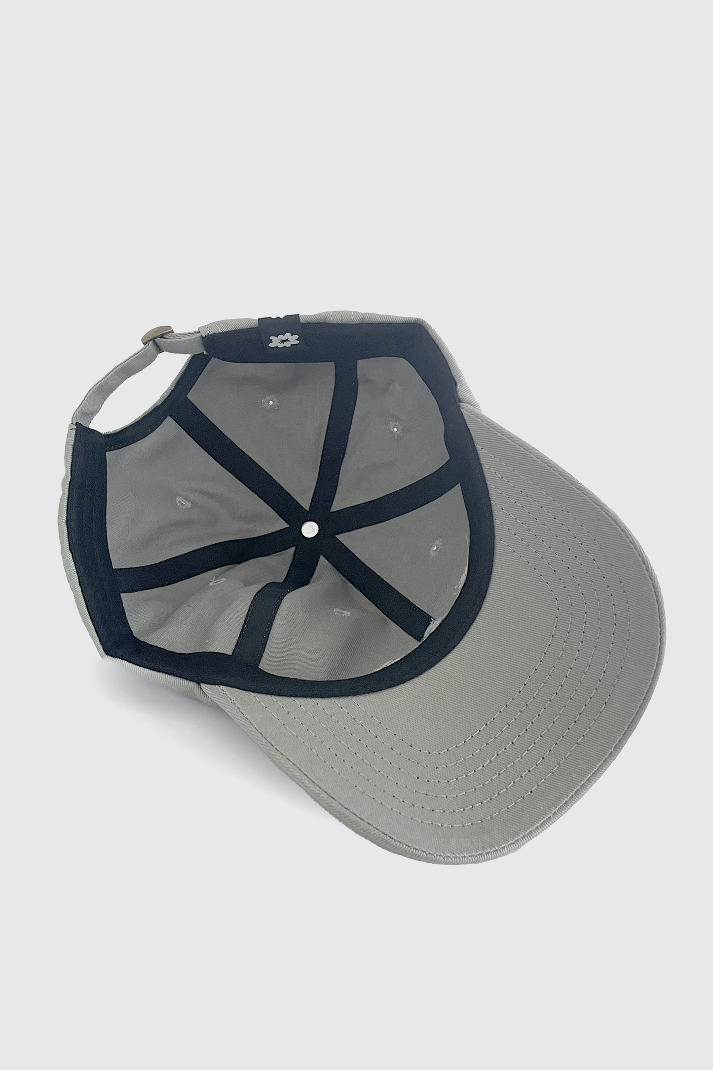 A inside view of the Chains Hat from Badaboöm Studio, featuring a chain and flower embroidered decal on a light grey baseball cap. It's shown against a grey background.