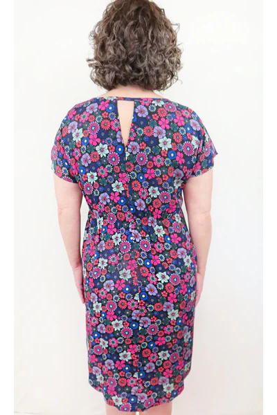 Beatrice Shift Dress by Mandala, Vintage Floral Purple, back view, round neck short sleeves, French darts, elastic at back of waist, tie belt, keyhole cutout at back of neck, pull-on, scooped knee-length hem, pockets, fully lined, sizes XS to XL, made in Ontario