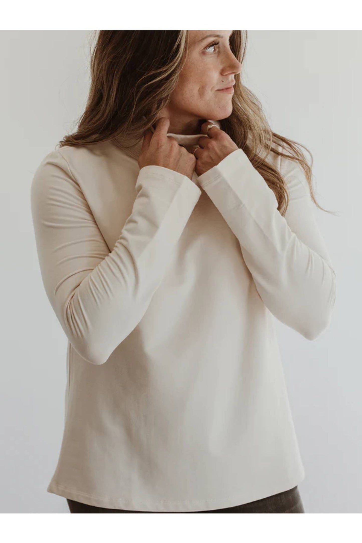 A close up of a woman wearing the Fauna Sweater by Blondie in Ivory, featuring an A-line shape, belled sleeves, and a mock rib neck.