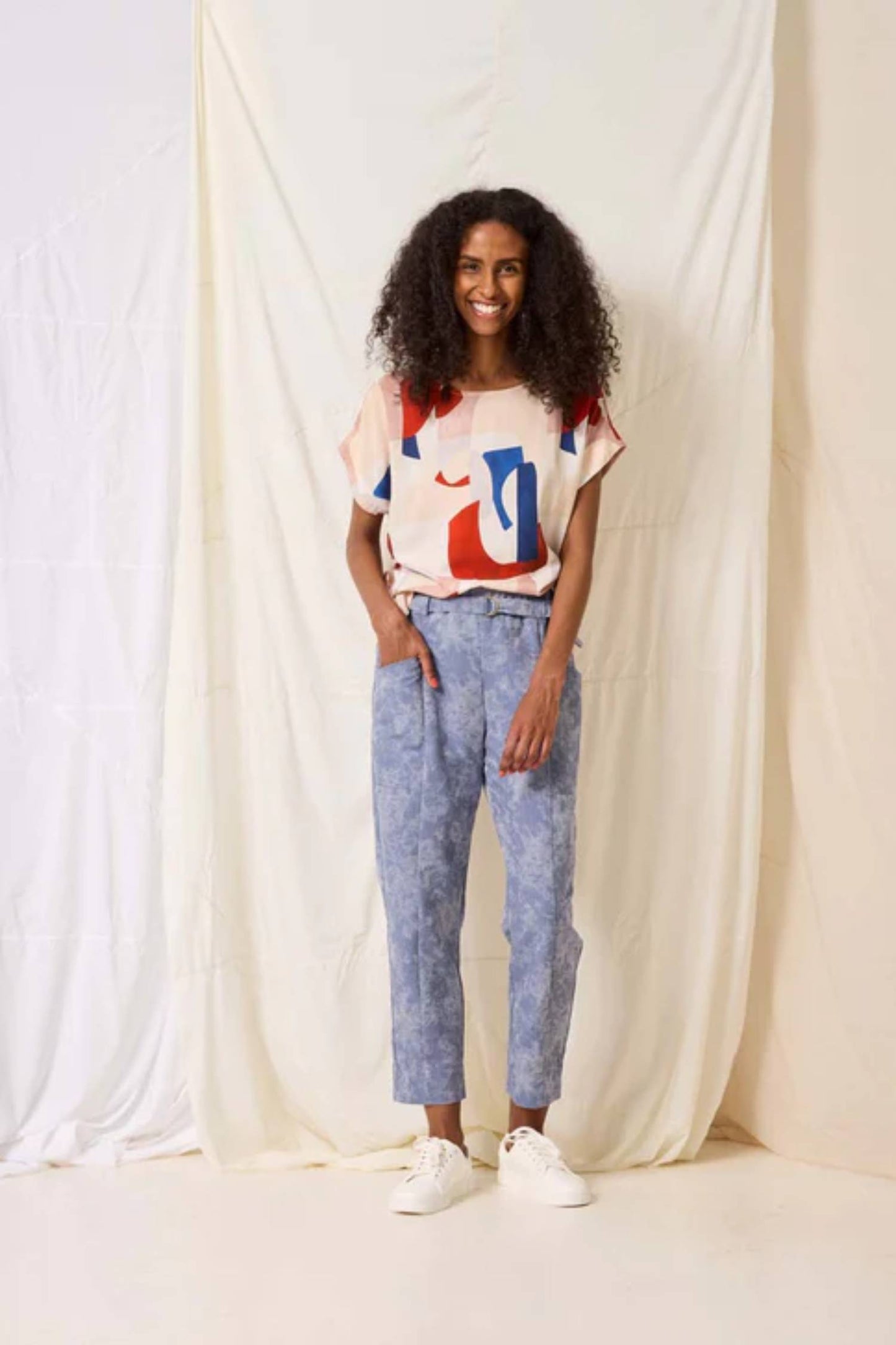 A woman wearing the Ombre Top by Cokluch in Vera print, standing in front of a white curtain