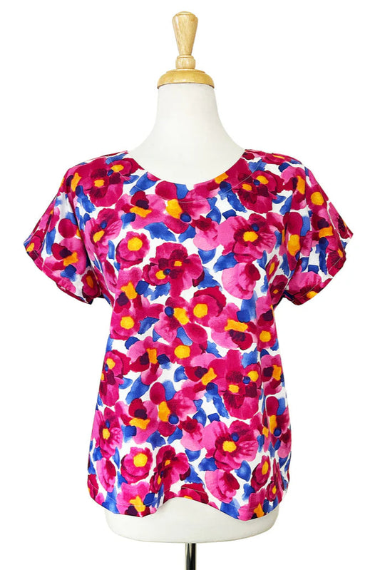 The Macaron Top by Desserts and Skirts in Pink Floral, with a round neck, short sleeves, and a loose fit, is shown on a mannequin against a white background.