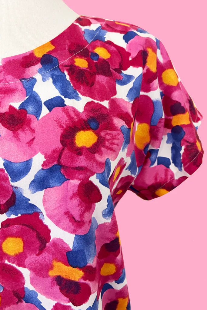 Close up detail of the sleeve of the Macaron Top by Desserts and Skirts in Pink Floral, shown on a mannequin against a pink background.