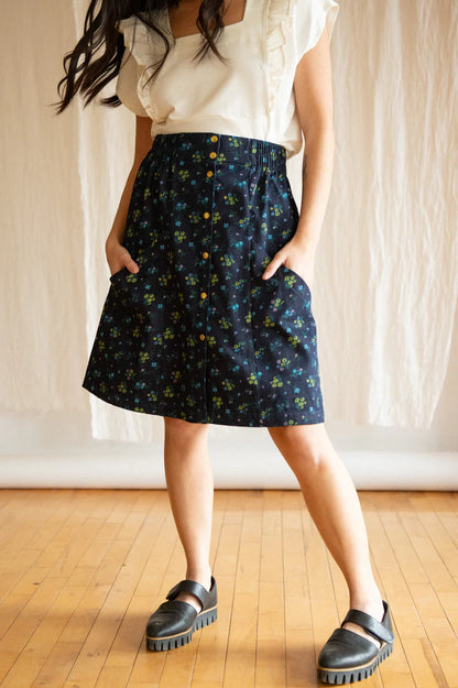 Chrysanthème Skirt by Kazak, Floral Denim, knee-length, A-line, elastic at sides and back of waist, brass buttons up the front, two large pockets, eco-fabric, organic cotton, OEKO-TEX certified, sizes XS to XL, made in Montreal 