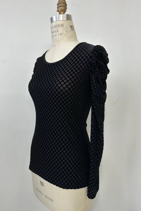 The Octavia Sweater by Kollontai, featuring black cut velvet in a diamond pattern, gathered shoulders, long sleeves, an oval neckline, and a slim fit, is shown on mannequin against a white background.