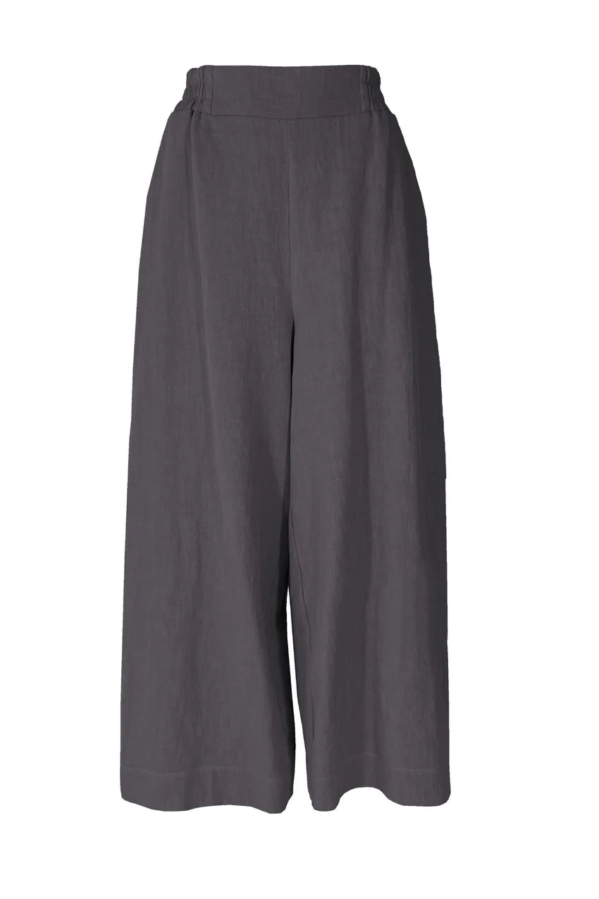 The Kurt Pants by Melow in Slate, featuring wide cropped legs, a flat-front elastic waist band, and slant pockets, are show in front of a white background.