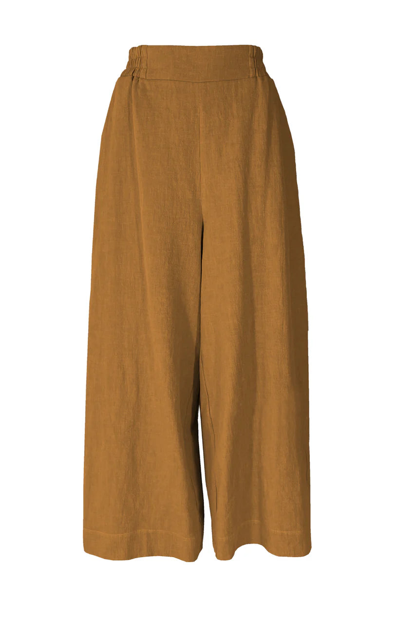 The Kurt Pants by Melow in Honey, featuring wide cropped legs, a flat-front elastic waist band, and slant pockets, are show in front of a white background.