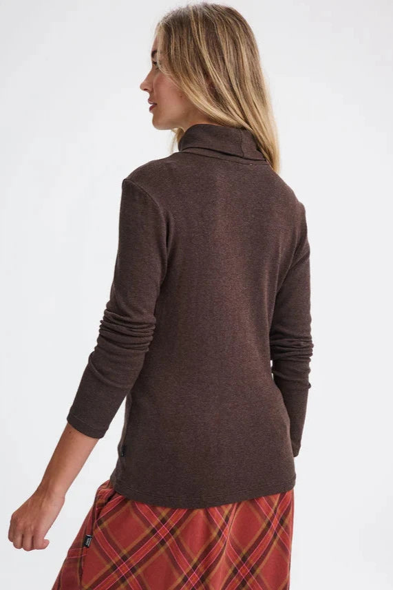 Back view of a woman wearing the Gatineau Turtleneck by Message Factory in Brown, a classic turtleneck in a bamboo and cotton blend, with an orange plaid shirt. She's standing in front of a white background.