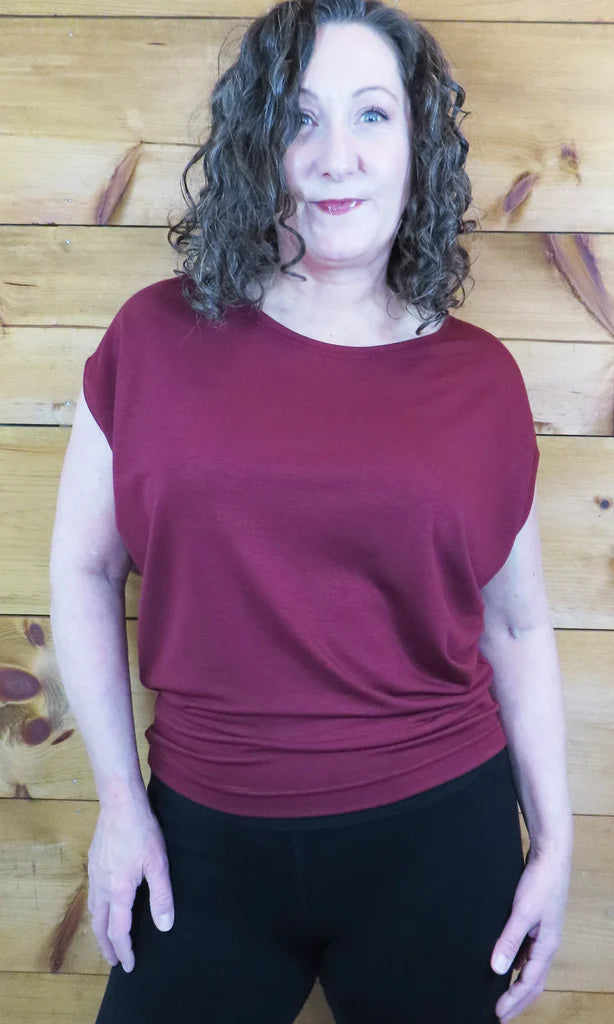 A woman wearing the Charles Slouch Tee by Mandala in Porto, standing in front of a wood panelled wall