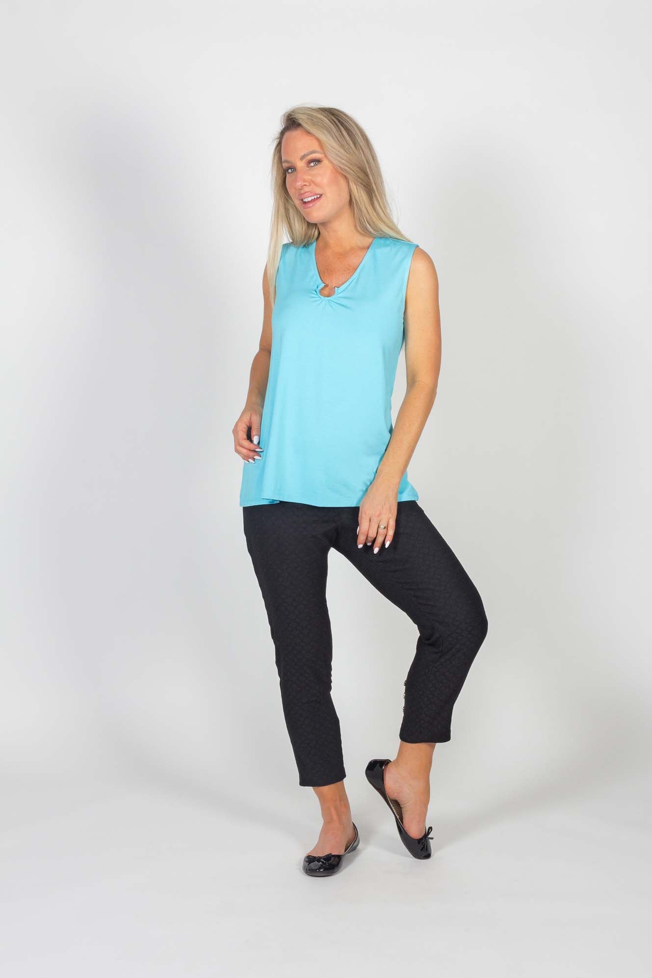 A woman wearing the Caroline Pant by Pure Essence in Black and a baby blue top standing in front of a white background