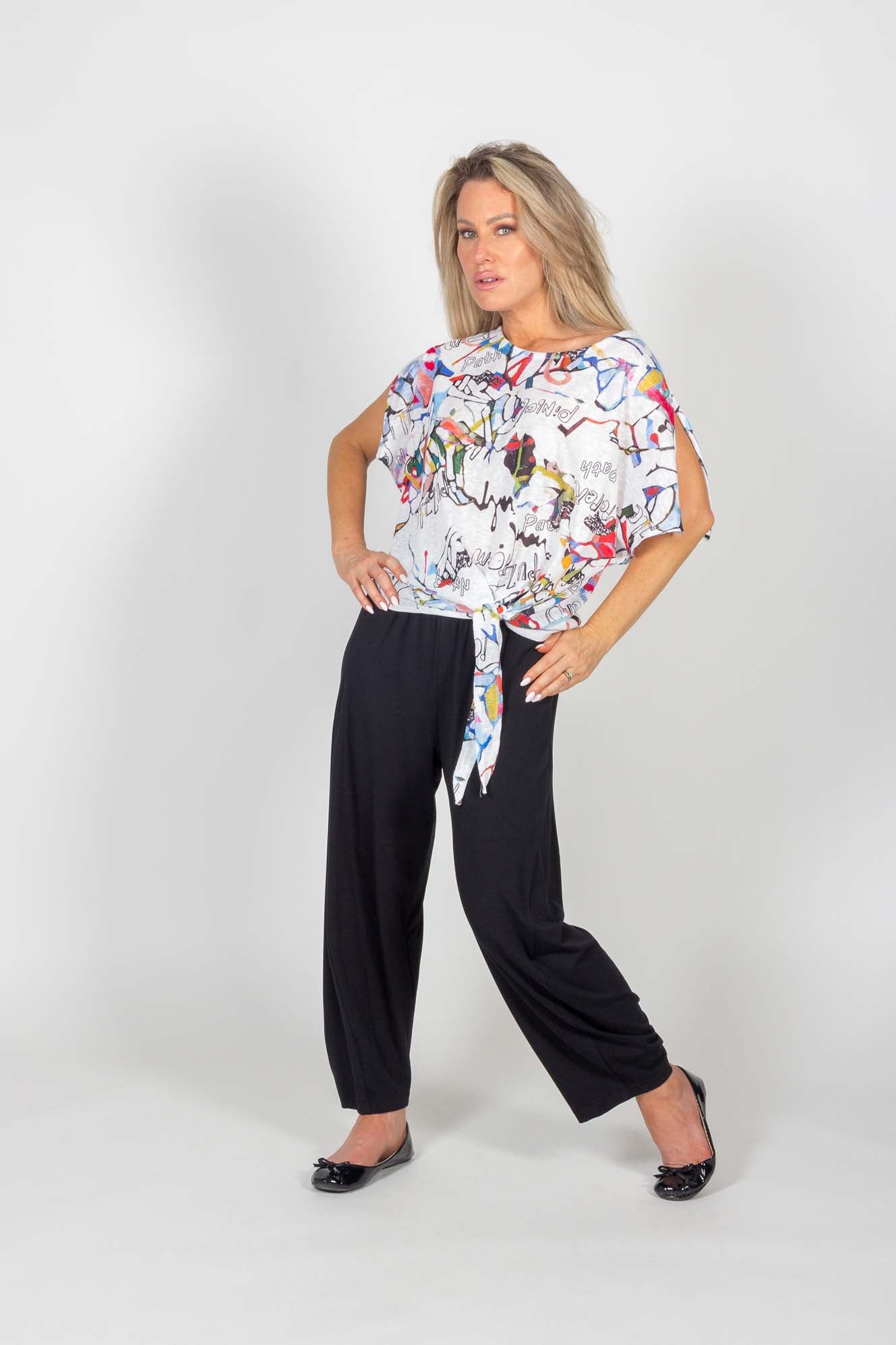 A woman wearing the Celeste Harem Capri by Pure Essence in Black, standing in front of a white background
