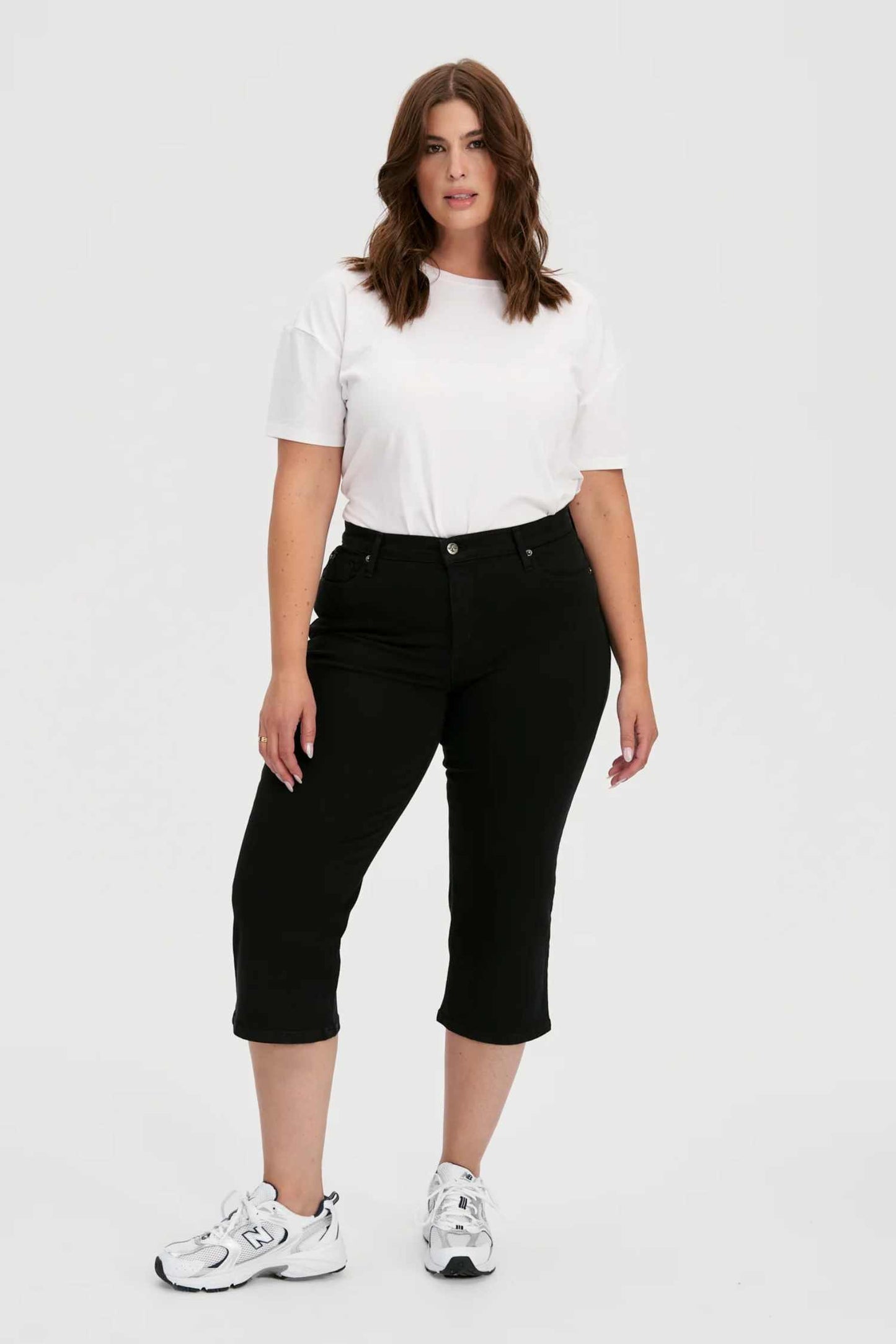 Woman wearing the CHLOE Classic Rise Straight Leg Capri Yoga Jeans in Black standing in front of a white background