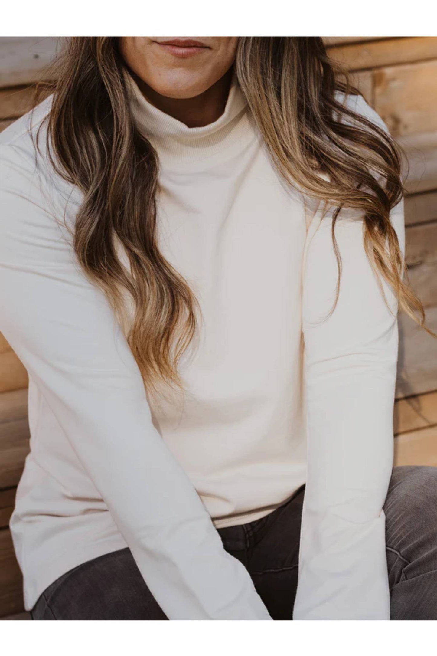 A close up of a woman wearing the Fauna Sweater by Blondie in Ivory, featuring an A-line shape, belled sleeves, and a mock rib neck.