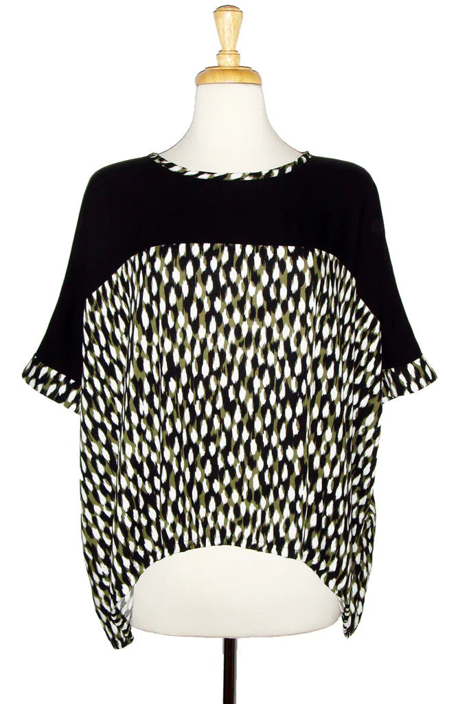The Chloe Top by Desserts and Skirts in Brush Green, featuring a round neck, batwing sleeves, and a loose and flowing fit, is shown on a mannequin in front of a white background.