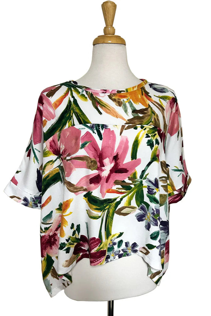 The Chloe Top by Desserts and Skirts in Garden Whimsy print, featuring a round neck, batwing sleeves, and a loose and flowing fit, shown on a mannequin against a white background