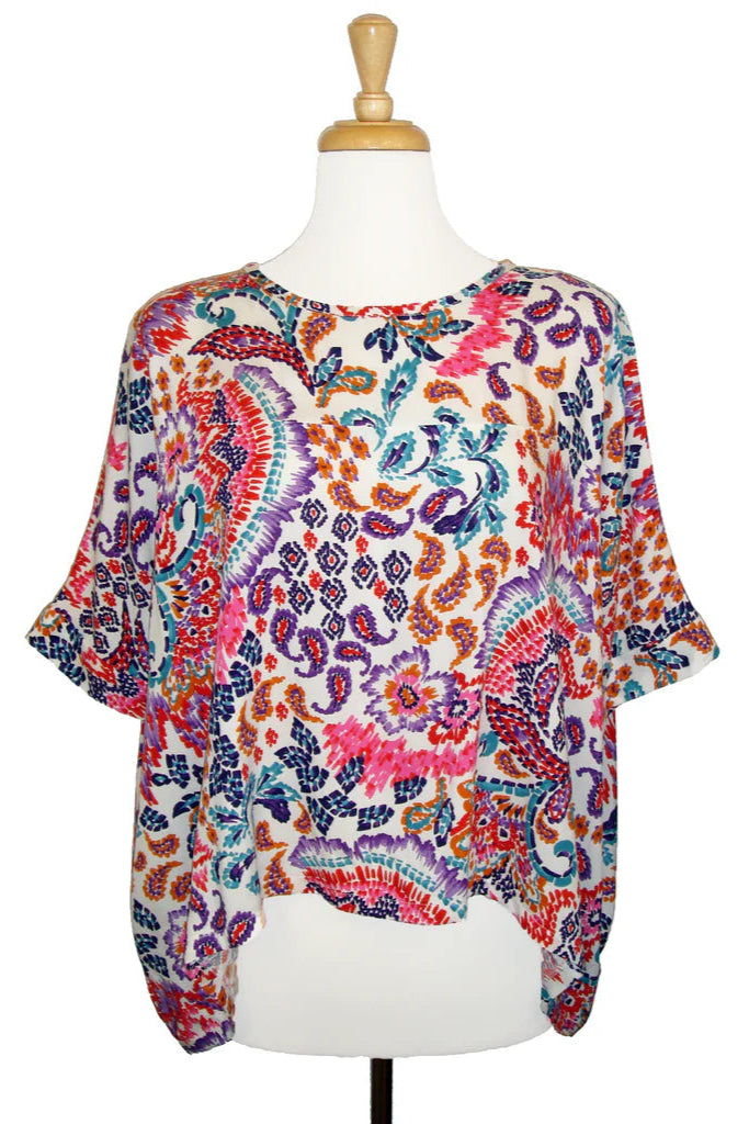 The Chloe Top by Desserts and Skirts in Paisley, featuring a round neck, batwing sleeves, and a loose and flowing fit, is shown on a mannequin in front of a white background.