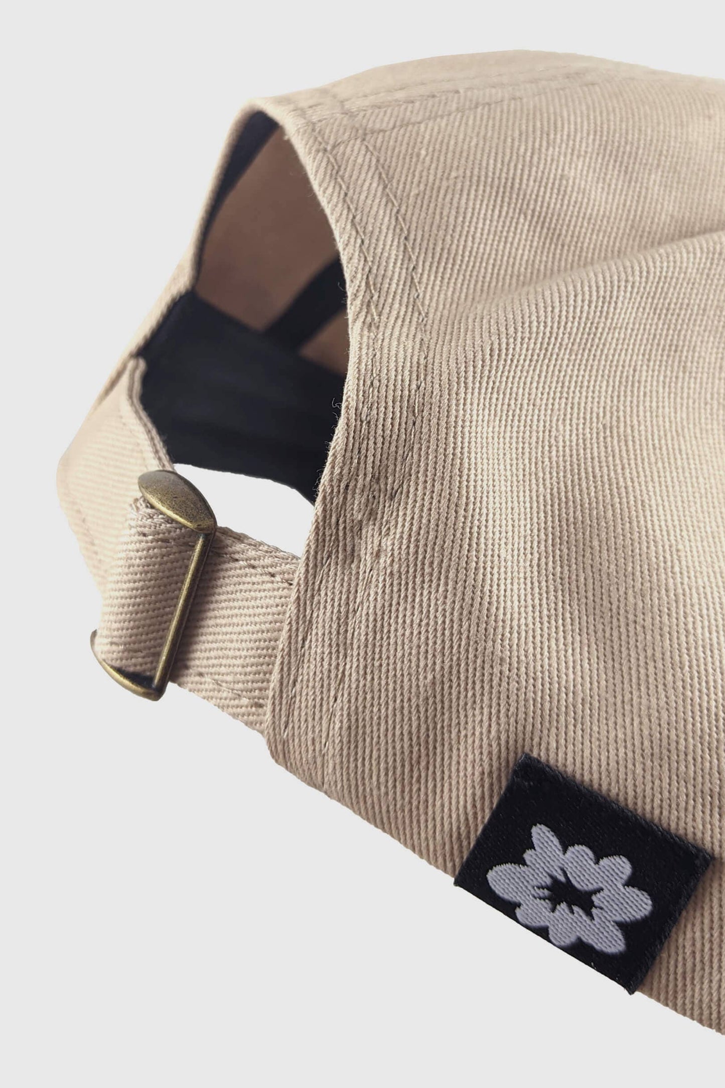 Close up of the back of the Reloading Hat from Badaboöm Studio featuring three embroidered skulls on a tan ball cap, shown against a light grey background.