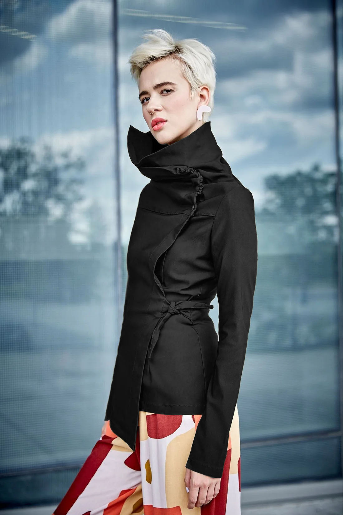Isabeau Jacket by Melow, Black, asymmetrical shape, high neck with snaps and cord, adjustable tie at the waist, slim fit with a flare at the hips, sizes XS to XXL, made in Montreal