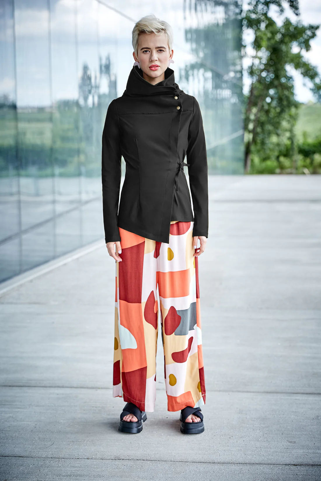 Isabeau Jacket by Melow, Black, asymmetrical shape, high neck with snaps and cord, adjustable tie at the waist, slim fit with a flare at the hips, sizes XS to XXL, made in Montreal