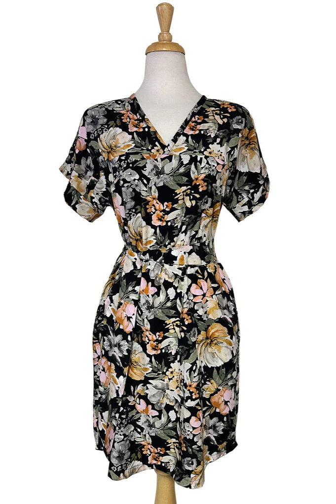 The Olivia Dress by Desserts and Skirts in Butter Floral, featuring short sleeves, a V-neck, a removable belt, and a knee length hem, is show on a mannequin in front of a white background.
