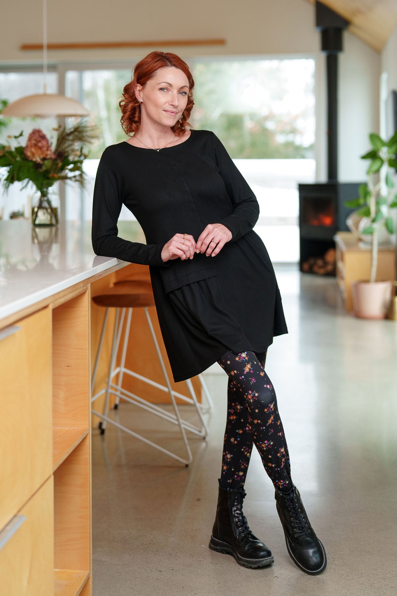A woman wearing the Laracin Leggings by Rien ne se Perd in a small Floral print, with a black tunic. She is standing in a kitchen.