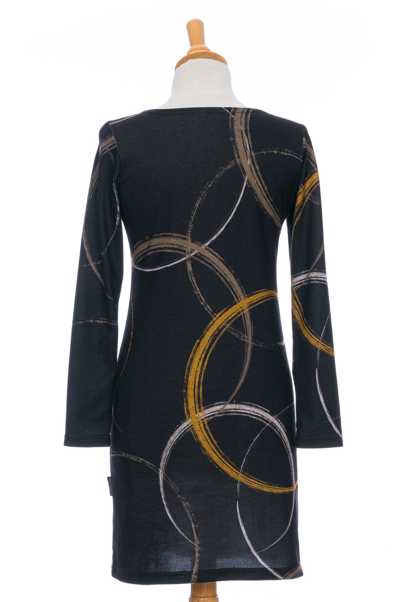 A back view of the Flore Dress by Rien ne se Perd in Bordure, a semi-fitted black dress with a flora inspired print, long sleeves, a round neck, and hem that hits above the knees, is shown on a mannequin in front of a white background.