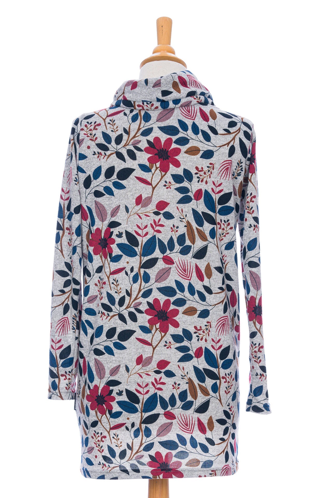 Back view of the Genevrier Tunic by Rien ne se Perd in Floral, featuring a turtleneck with a drawstring, a kangaroo pocket, long sleeves, and a straight cut, is shown on a mannequin in front of a white background.