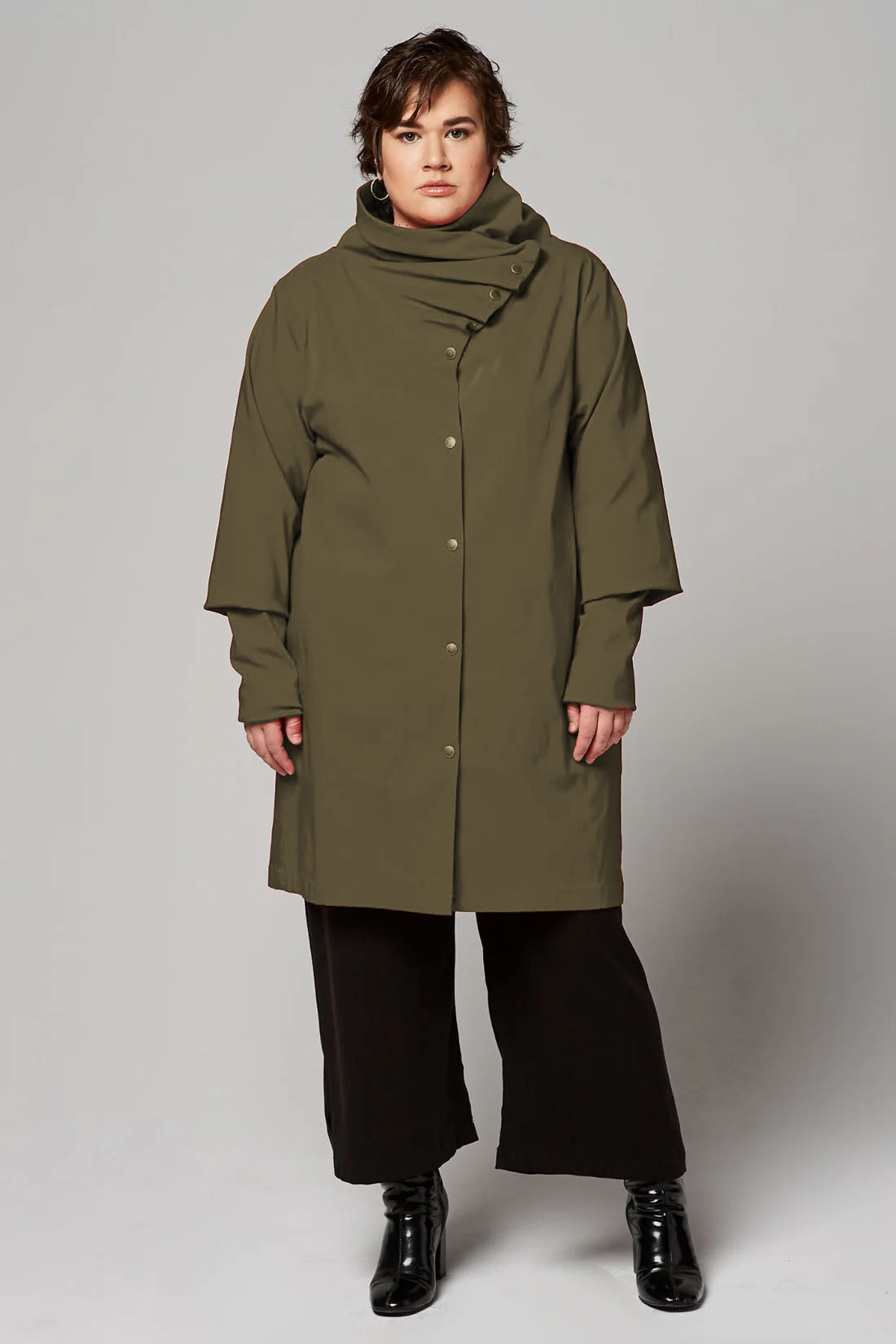 A woman wearing the Ubert Jacket by Melow in Olive, standing in front of a white background