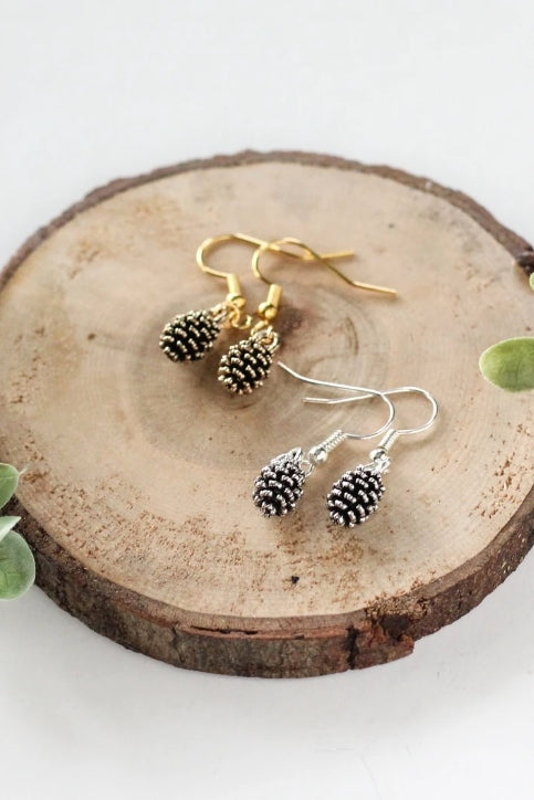 Pine cone earrings by Birch Jewellery; silver and gold, styled on a stump of wood