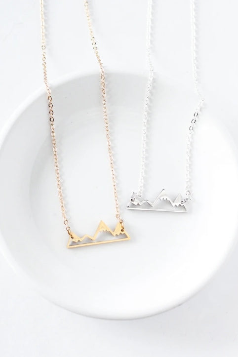 Mountain necklace by Birch Jewellery; silver and gold; flat lay styled on a white ceramic dish