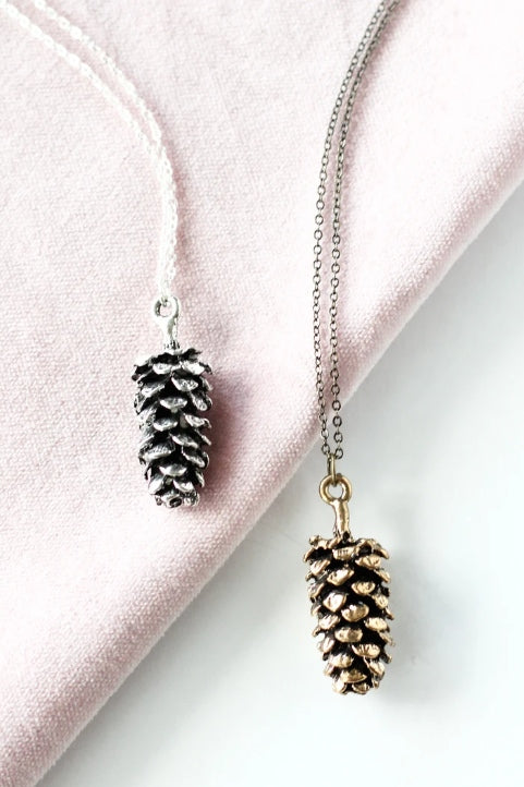 Large pine cone necklace by Birch Jewellery; flat lay; in silver and gold