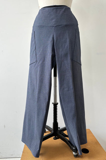 The Frydek Pants by Kollontai in Denim, featuring wide legs, a wide pull-on waistband, and angled patch pockets, are shown on a mannequin in front of a white background. 