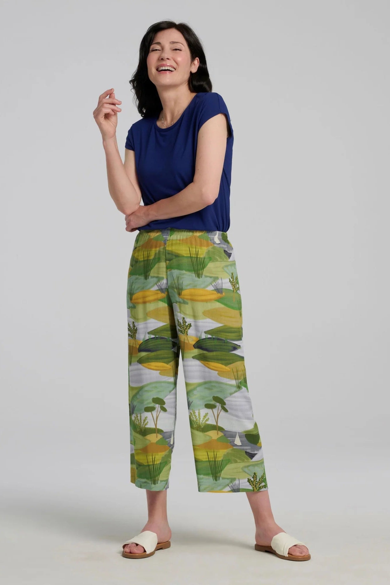 A woman wearing the Eowyn T-Shirt by Kollontai in Admiral with the Paraiso pants, she is standing against a grey background.

