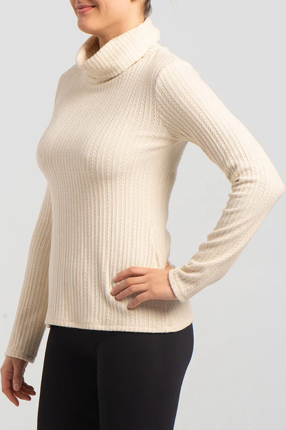 Side view close up of a woman wearing the Garfunkel Sweater by Kollontai in Cream with black pants, standing in front of a white background 