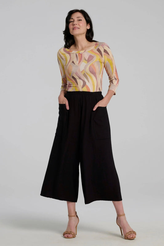 A woman wearing the Vellina Top from Kollontai in Peach print, a 3/4 sleeve fitted top with a wide neck. She is wearing it with black wide-leg pants against a plain background