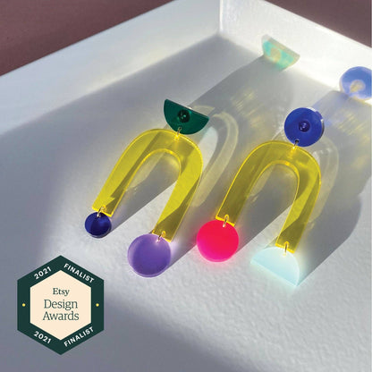 Colorful earrings on a white surface with Etsy Design Awards 2021 Finalist badge.