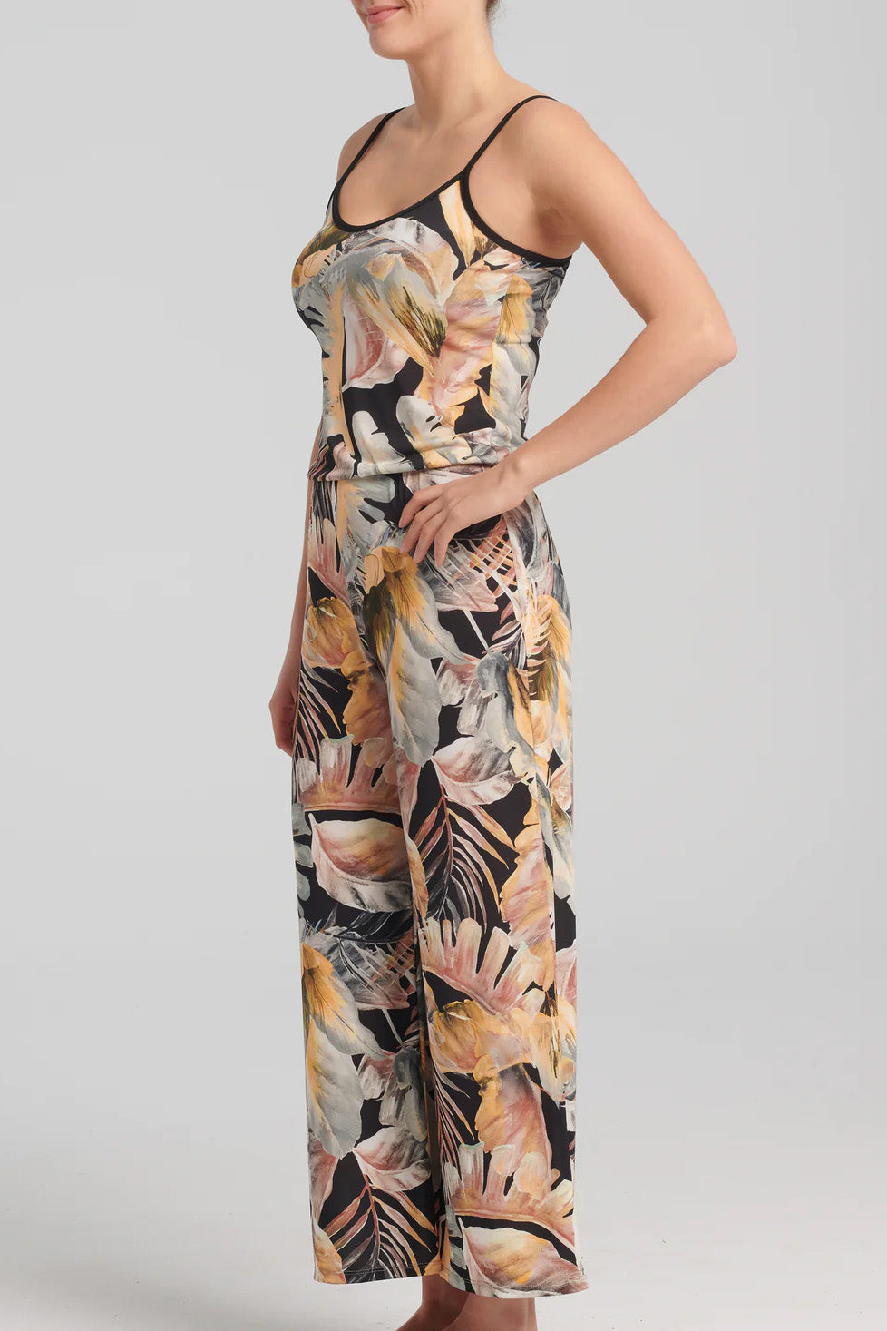 Nephele Jumpsuit by Kollontai, side view, neutral toned tropical print, black piping at neckline and  spaghetti straps, bloused effect at waist, sizes XS to XL, made in Quebec