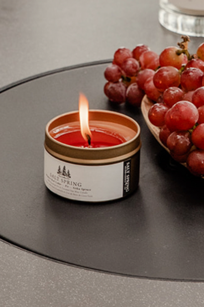 Candlelit table setting with grapes, cookies, and drinks outdoors.