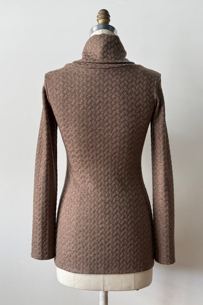 A back view of the Eloi Sweater by Kollontai in Brown, a slim fitting textured sweater with a large crossover collar, is shown on a mannequin against a white background.