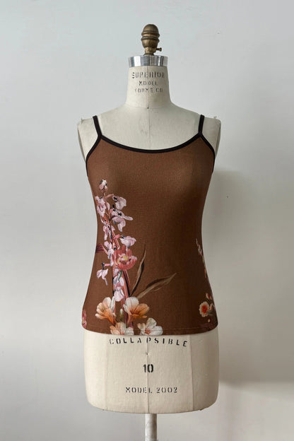 The Morganne Top by Kollontai, a brown floral tank top with spaghetti straps, is shown on a mannequin against a grey background