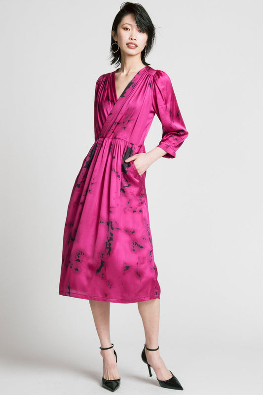 A woman wearing the Therapy Dress by Allison Wonderland in Pink Print, with a faux wrap front, gathers at the shoulders cuffs and waist, and a full midi-length skirt. She is standing in front of a white background. 