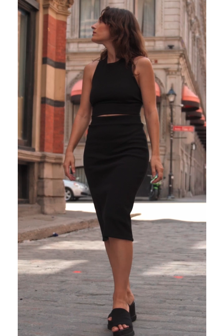 A woman wearing the Cartagena Skirt by MAS in Pepper, standing on a cobblestone street