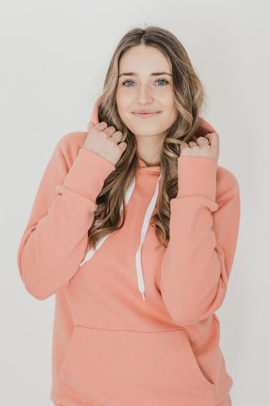 A woman wearing the Classic Forest Hoodie by Blondie in Tawny, standing in front of a white background