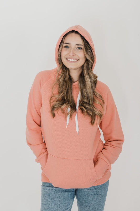 A woman wearing the Classic Forest Hoodie by Blondie in Tawny, standing in front of a white background