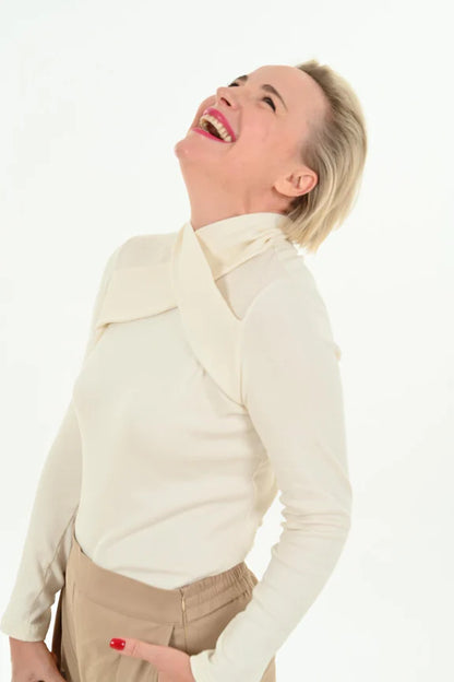 Waist-up shot of a woman wearing the Irina Sweater by Julei Design in Vanilla, standing in front of a white background 