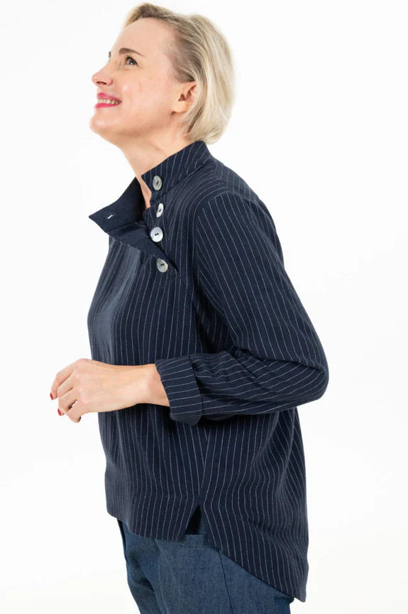 Side view of a woman wearing the Charlie Top by Julei Design in Navy Stripe with the Alice Cocoon Pant in Denim, standing in front of a white background