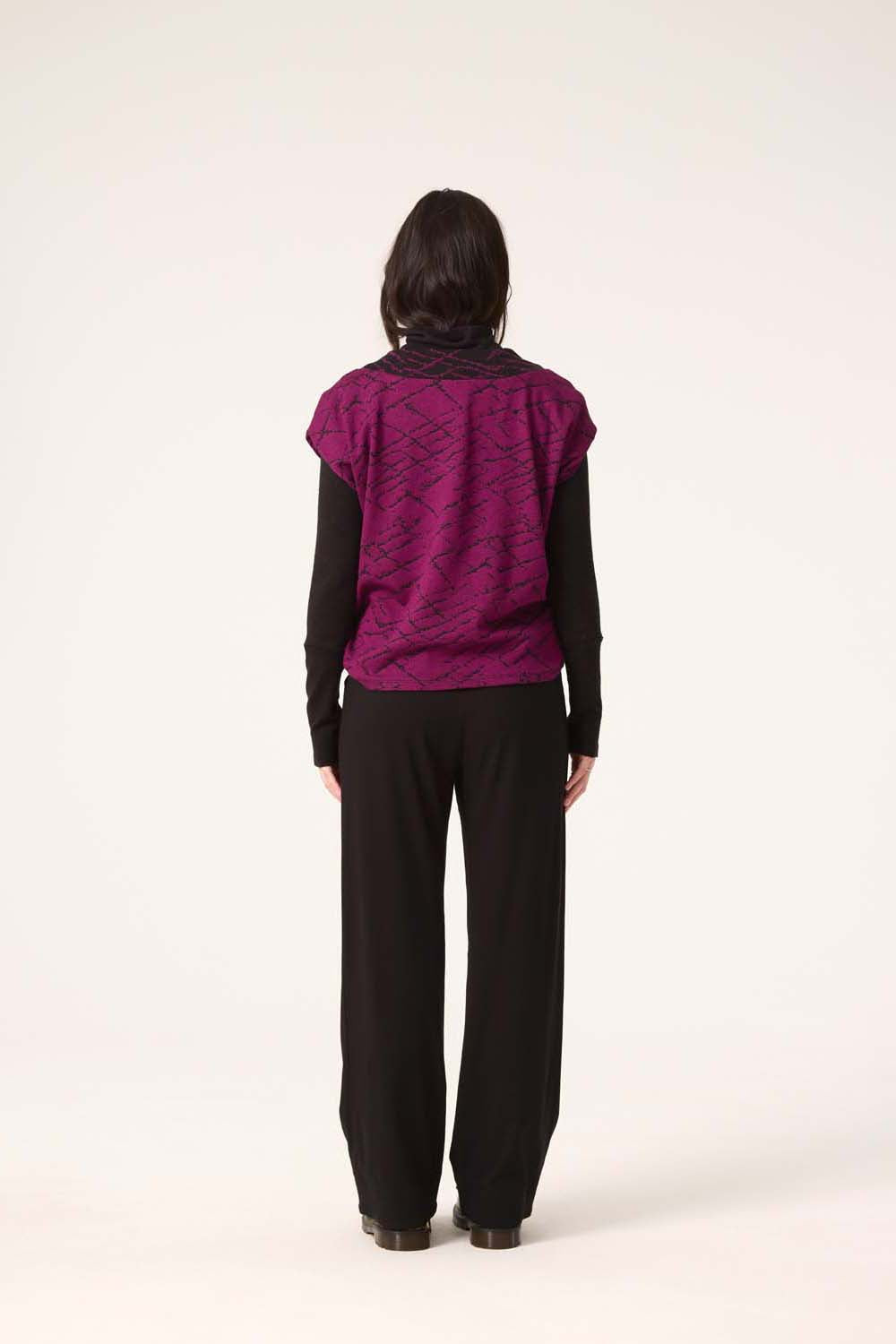 Back view of a woman wearing the Centaur Top by Cokluch in Magenta with Black pants, standing in front of a white background 