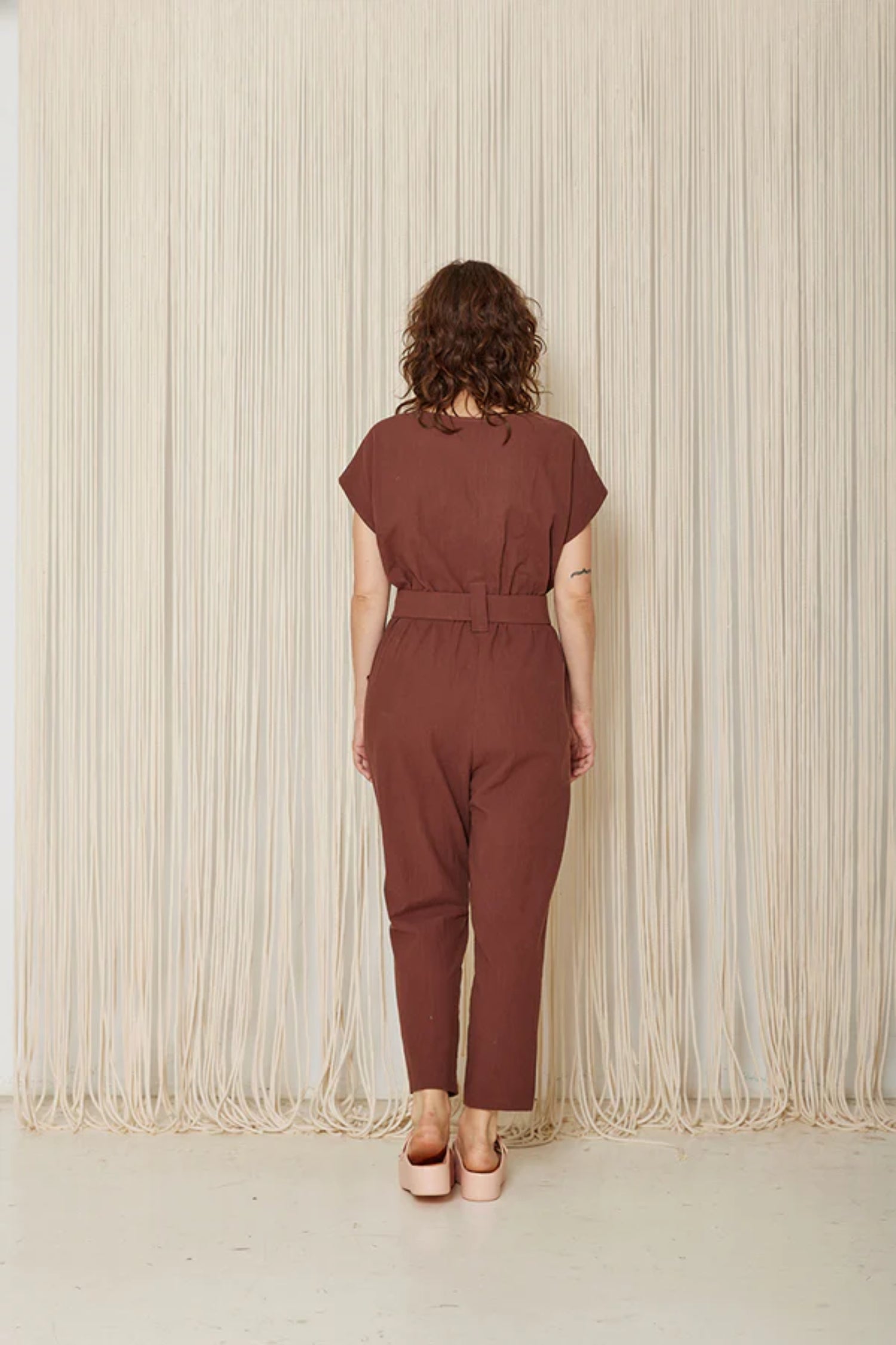 Arnica Jumpsuit by Cokluch, Sumac, back view, short extended sleeves, round neck, front button placket, loop-buckle belt at waist, ankle-length, eco-fabric, cotton, sizes XS to XL, made in Montreal 