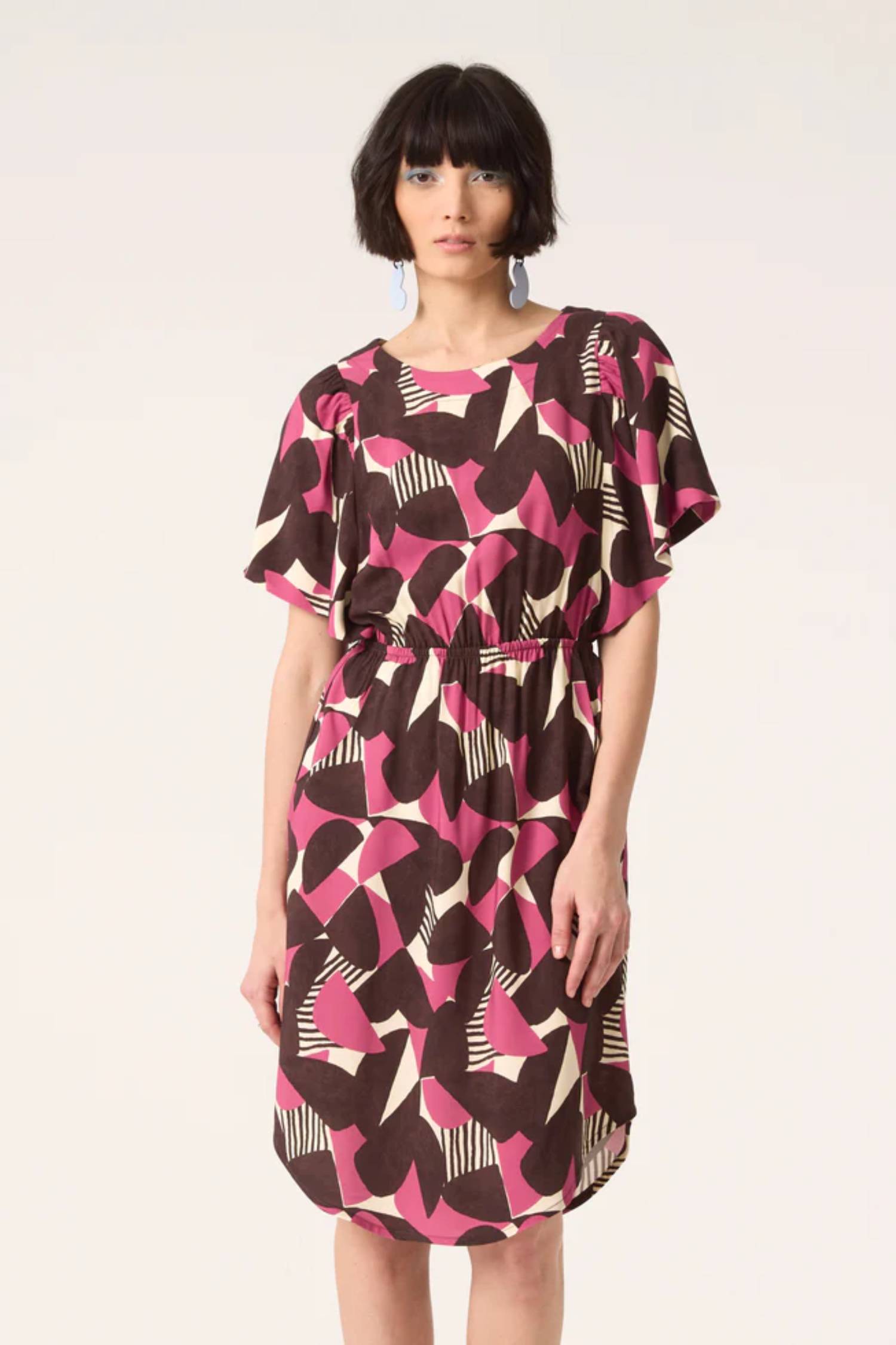 A woman wearing the Gemma Dress by Cokluch in Half Moon Berry print, standing in front of a white background